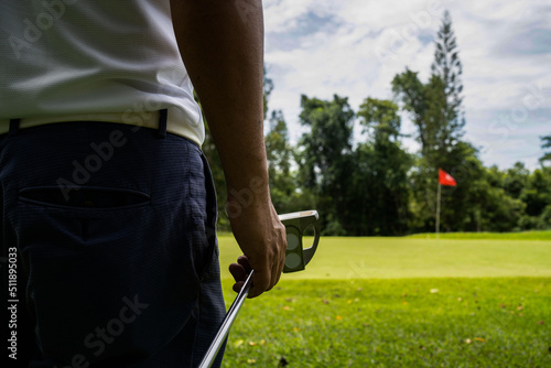 man white shirt blue pants In his hand, the putter prepares for the next golf shot.