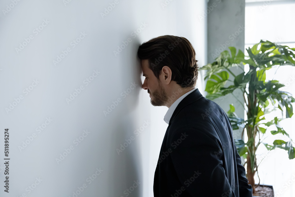 Upset businessman banging his head against wall in despair looks stressed having problems at work, bankruptcy, business failure unsuccessful negotiations, project loss, failed job interview concept - obrazy, fototapety, plakaty 