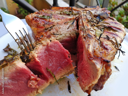 Grilled Florentine T-bone beef steak cut in a round white plate photo