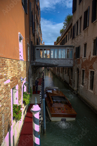 Venice, Italy - September 03, 2018: Helmsman in tuxedo next to boat in a canal against Pont des Soupirs (Bridge of sighs)