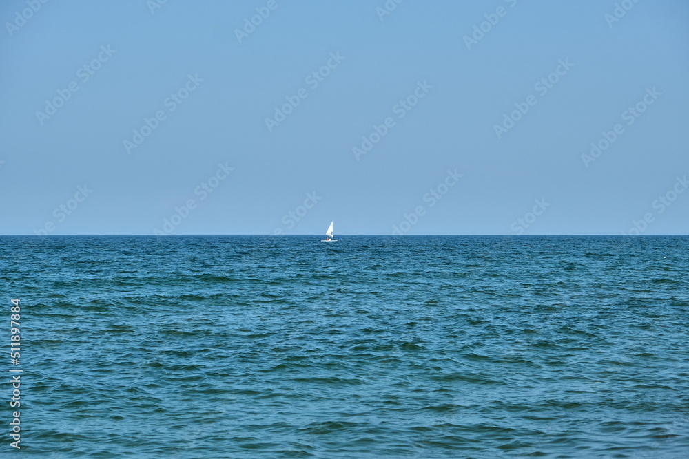Small white boat sailing across a beautiful turquoise sea.
