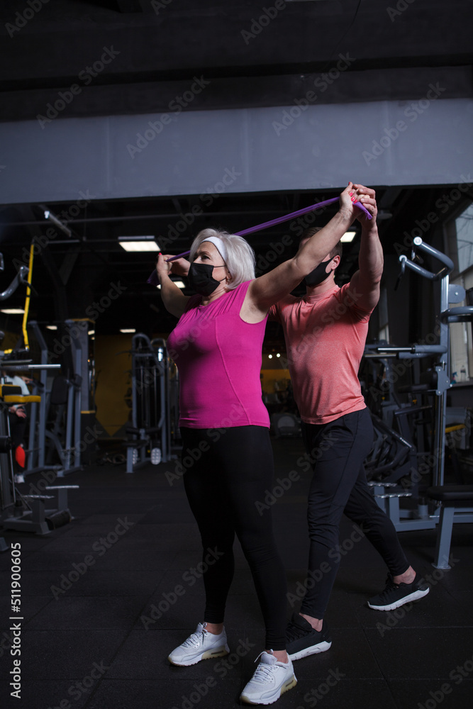 Senior woman wearing medical face mask, working out at gym during coronavirus pandemic Senior woman wearing medical face mask, working out at gym during coronavirus pandemic