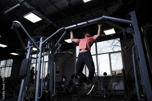 Low angle shot of a sportsman doing pull-ups at the gym