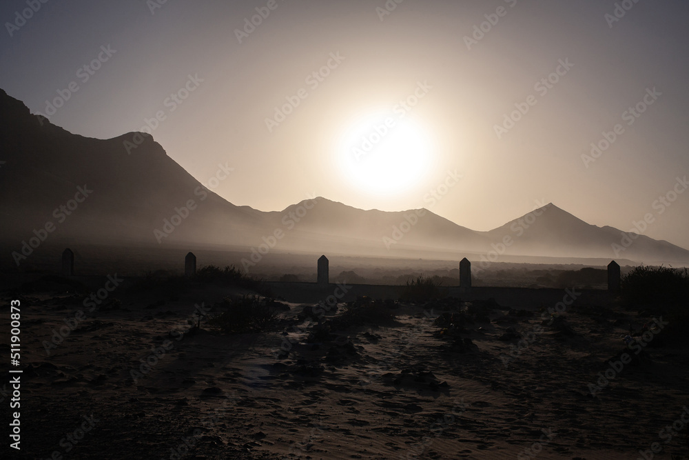 Ancient cemetery sillрoutte against the backdrop of volcanoes at sunset  at Pajara beach Fuerteventura
