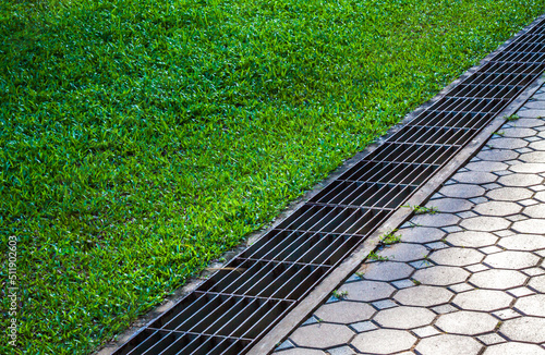 waterway and road - grass. Aqueduct between nature and city. water drain in garden field. Steel rusty grating in the Grass garden and concrete. Manhole cover metal and way - grass. drainage. sewer.