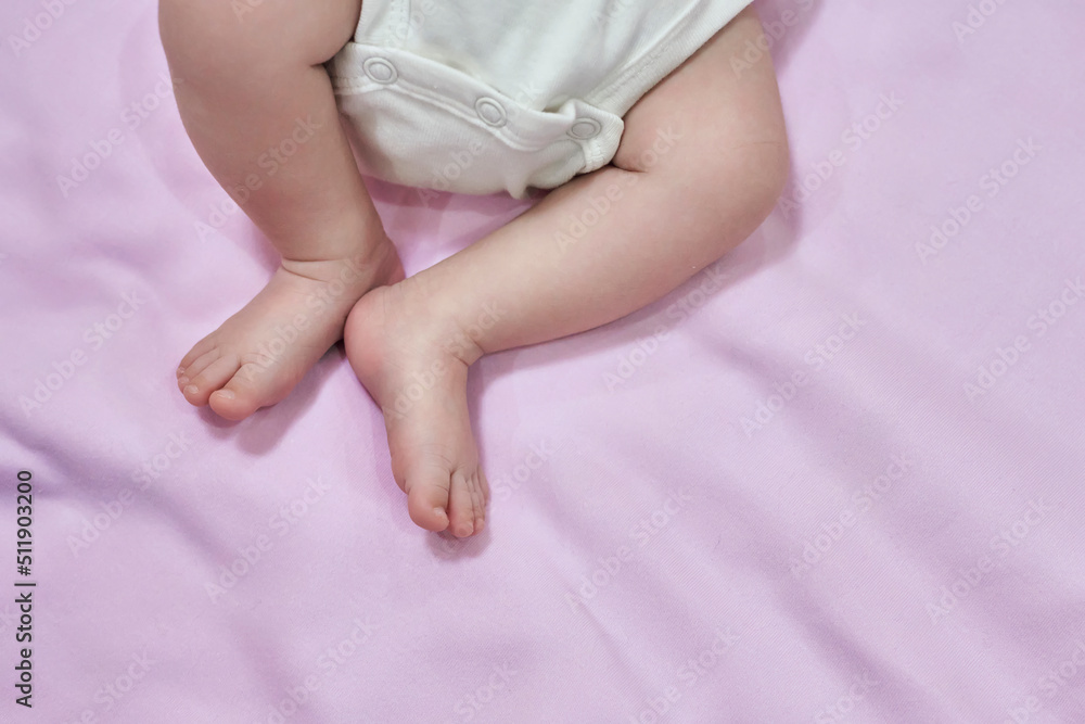 Low Section Of Baby Feet Relaxing Over Blanket. Feet of the infant lying on pink backgraund Low Section Of Baby Feet Relaxing Over Blanket. Feet of the infant lying on pink backgraund