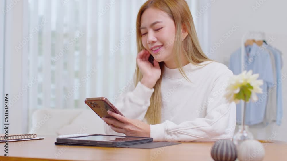 Happiness young woman wear casual use mobile phone for shopping online enjoy with social media and surf internet to relax at home. Asian Female having fun with game or lifestyle apps. online banking Happiness young woman wear casual use mobile phone for shopping online enjoy with social media and surf internet to relax at home. Asian Female having fun with game or lifestyle apps. online banking