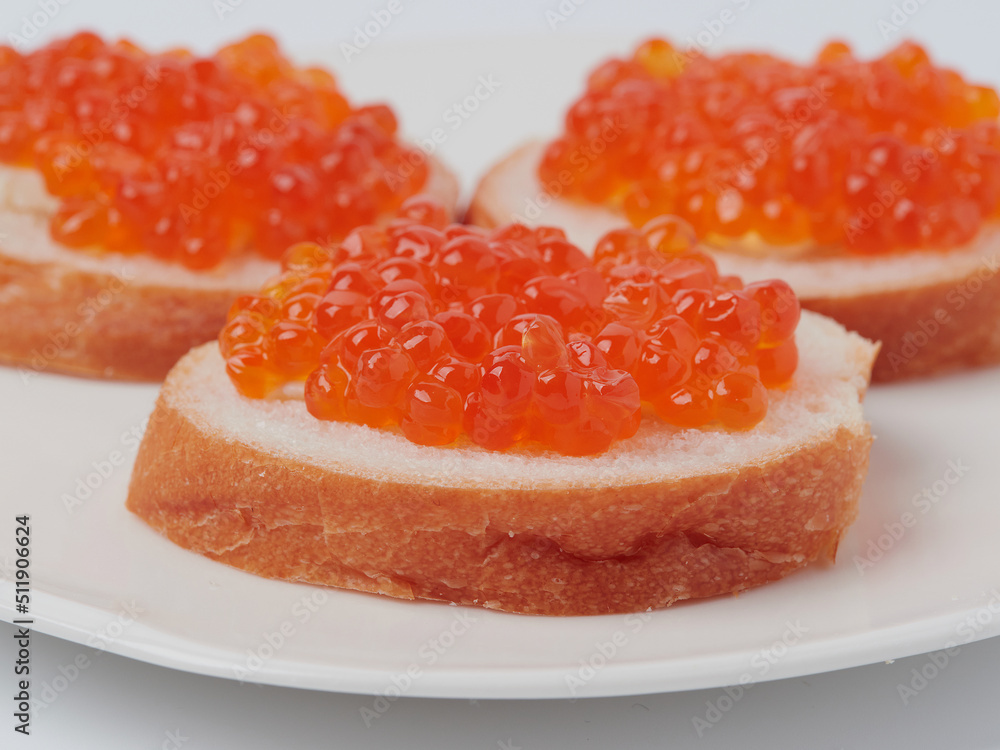 A red caviar sandwich on a plate on a white table
