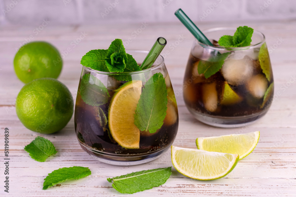 Two cuba libre cocktails of cola, lime and mint.
Two cuba libre cocktails of cola, lime and mint.