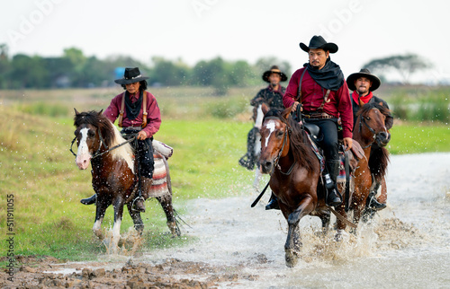 Group of cowboy and cowgirl ride horse through water in reservoir with day light.
