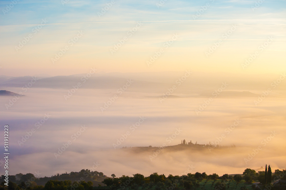 Picturesque view of countryside  of Tuscany in the light of the rising sun in foggy morning, Italy
