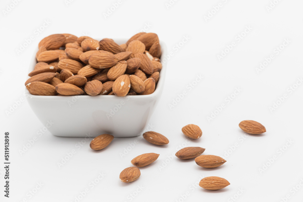 bowl with peeled almonds on a white background, one almond out of the bowl bowl with peeled almonds on a white background, one almond out of the bowl