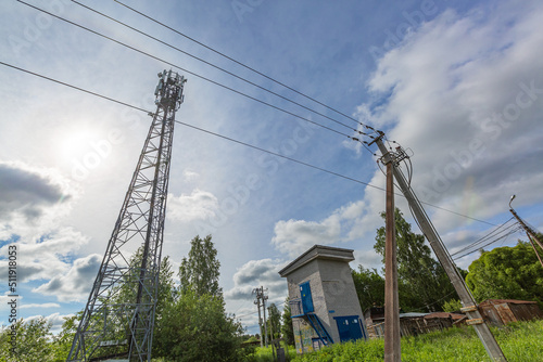 Telecommunication tower or mast with microwave, radio panel antennas, outdoor remote radio units, power cables, coaxial cables, optic fibers and the electrical pole with cables and electrical