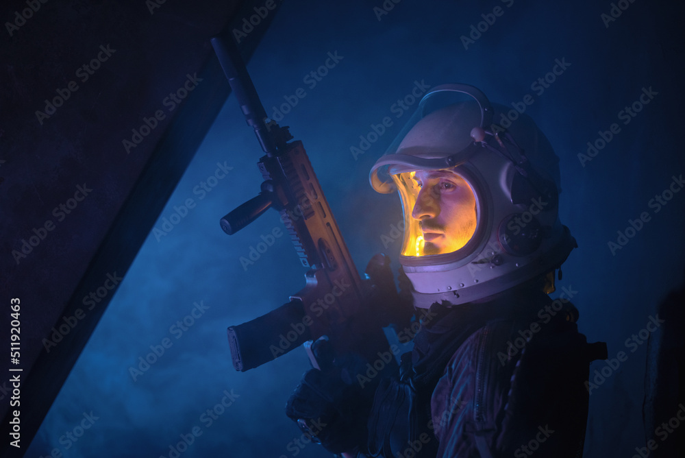 Spaceman or star trooper in the helmet and with rifle in the blue smoke. Science fiction concept.
