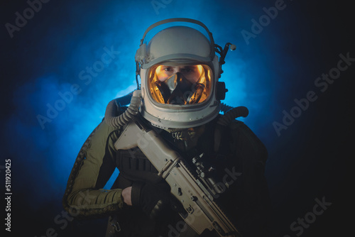 Spaceman or star trooper in the helmet and with rifle in the blue smoke. Science fiction concept. photo