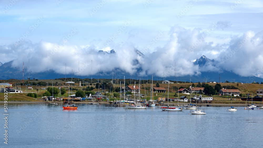 Sailboats moored in the harbor in Ushuaia, Argentina, beneath cloud shrouded mountains
