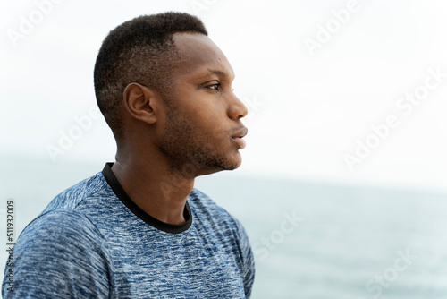 Handsome fitness multiracial man at the beach on a summer day standing in relaxed pos