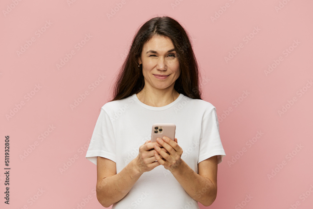 portrait of a beautiful woman with long hair with a fashion phone in her hands, in a white T-shirt, on a pink background portrait of a beautiful woman with long hair with a fashion phone in her hands, in a white T-shirt, on a pink background