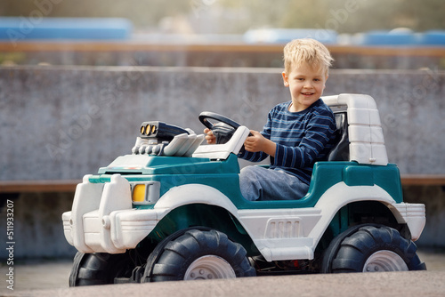 Smiling little boy driving big toy car ,Child enjoying warm summer day.