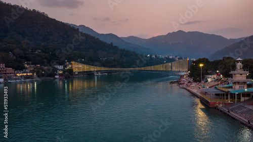 iron suspension bridge illuminated with ferry lights with ganges riverbank view at evening aerial