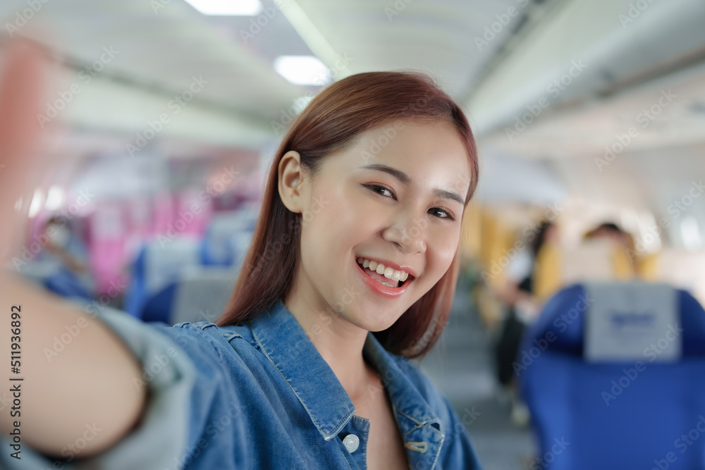 Fototapeta premium Travel, tourism business, portrait of a woman using her phone selfie on an airplane to post a profile picture of herself