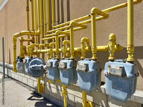 Nature gas cubic meters in a row with yellow gas supply pipes on exterior wall of building. Energy provider, bill, heating, price hike, crisis, measurement, consumption and cost saving background. photo