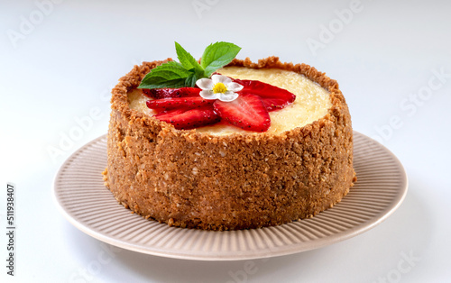 New York cheesecake is a dessert that is an open pie or even a cake. Decorated with strawberries. It consists of two main parts: sand base and cheese filling. White background.