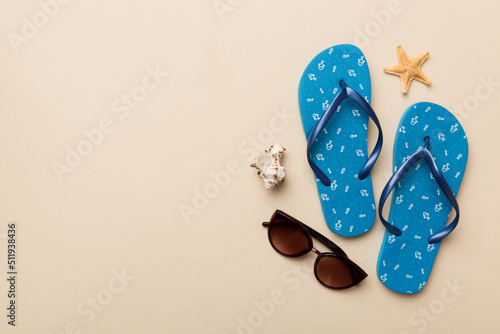 Summer travel concept. Flip flops, sunglasses and starfish on white. Top view on colored background