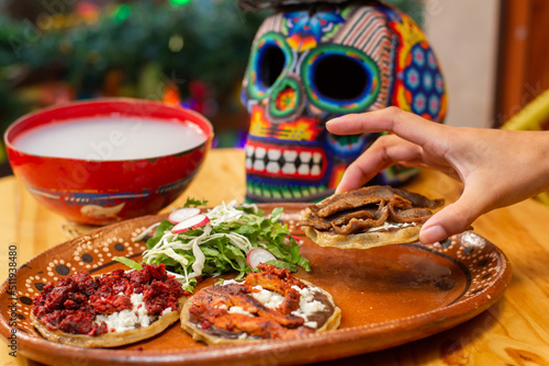 Canvas Print hand taking Mexican meat sopes from traditional dia de muertos offering