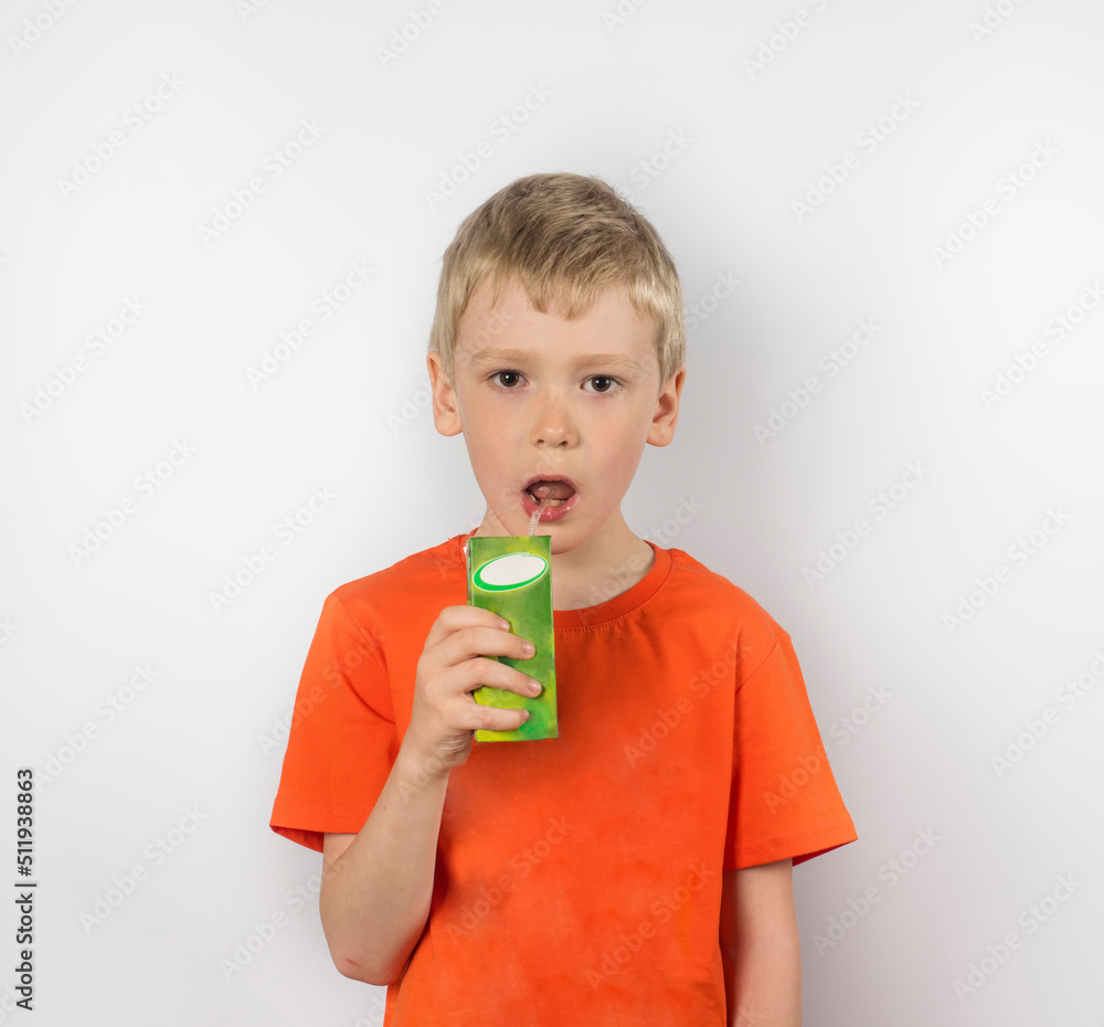 a boy in an orange T-shirt drinks apple juice from a box. a boy in an orange T-shirt drinks apple juice from a box.