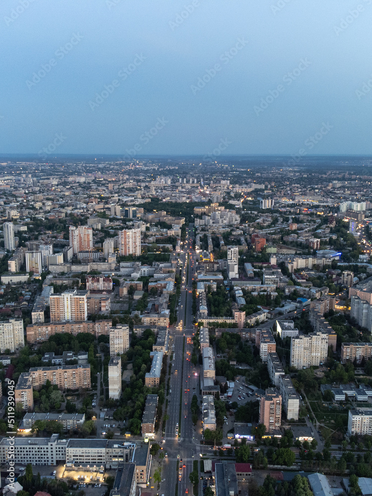 Aerial view Kharkiv city center Nauky avenue. Pavlove Pole and Central area with multistory high buildings in evening with street lights illumination. Vertical
