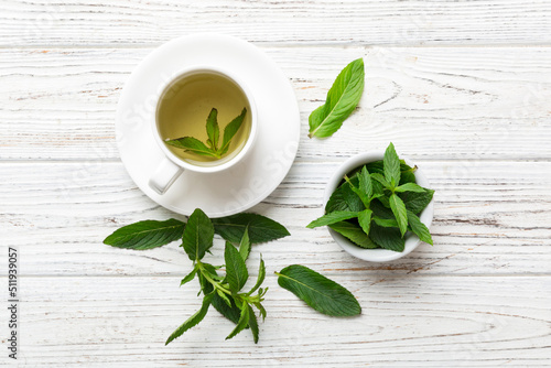 Cup of mint tea on table background. Green tea with fresh mint top view with copy space