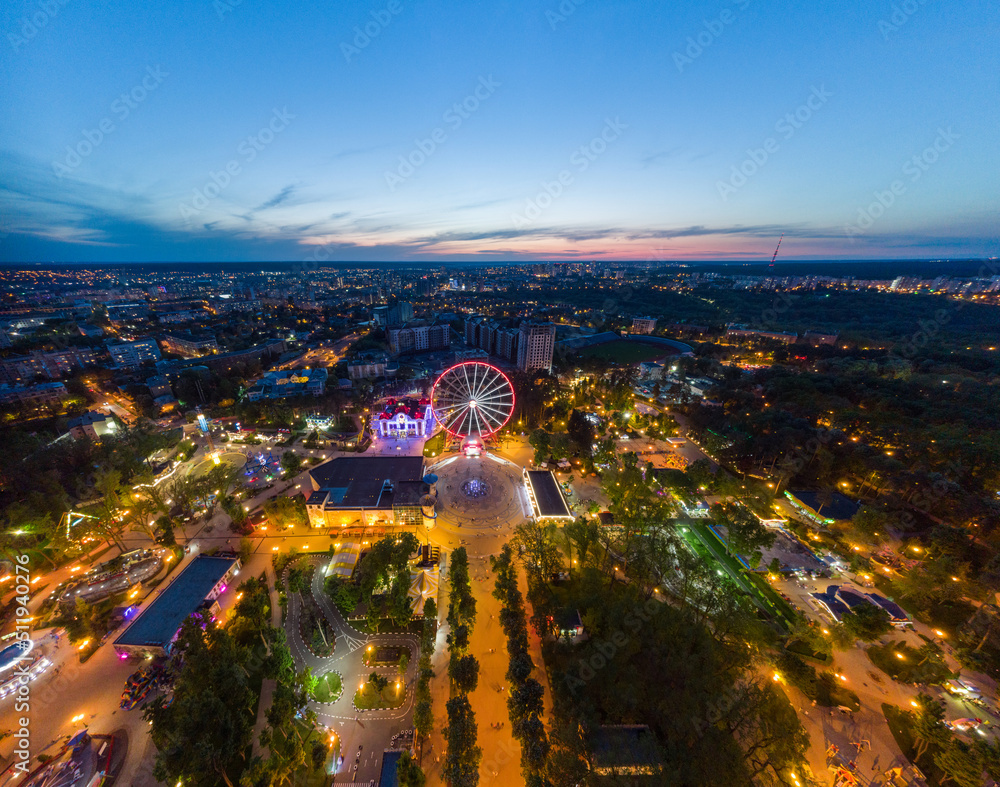 Aerial view on vivid evening cityscape, Ferris wheel and entertainments panorama. Kharkiv city center in sunset light, amusement Gorky Central Park, Ukraine