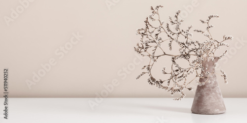 Dried flowers in vase on table. Bouquet of dried wild flowers on shelf on background beige wall.