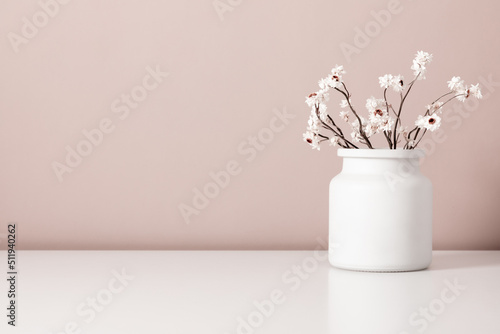 Dried flowers in vase on table. Bouquet of dried wild flowers on shelf on background beige wall.