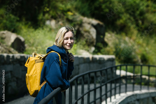 Portrait of a woman tourist with a yellow backpack on the road.
