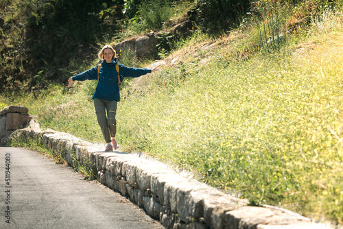 A female traveler walks merrily along a bump in the road beside a country road. © De Visu