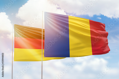 Sunny blue sky and flags of romania and germany