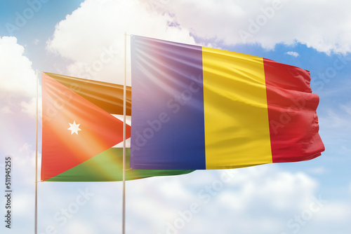 Sunny blue sky and flags of romania and jordan