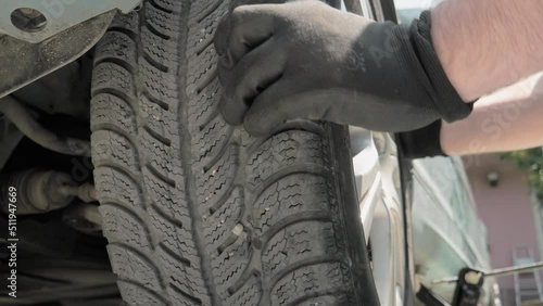 The hands of a service technician who checks the car wheel. Low angle, close up shot