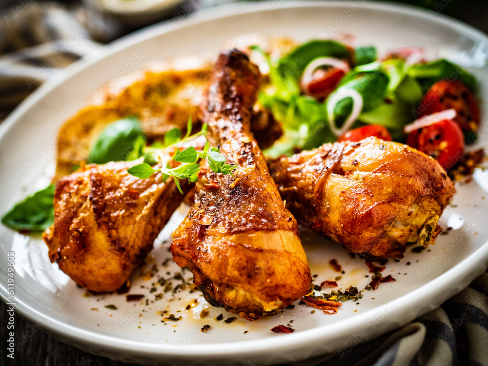 Barbecue chicken drumsticks with fried potato, lettuce and mini tomatoes on wooden table
Barbecue chicken drumsticks with fried potato, lettuce and mini tomatoes on wooden table