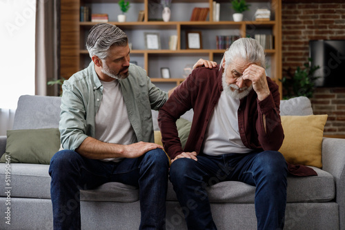 An elderly father complains about life to an adult son, which help him to calm dawn. Two generations family has conversation, sharing news, spending time together. Understanding, care and support. photo