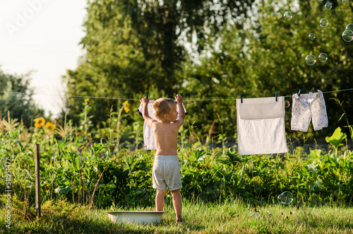 Boy hanging clothes on the street. Baby clothes are drying on the street. Selective focus. nature.