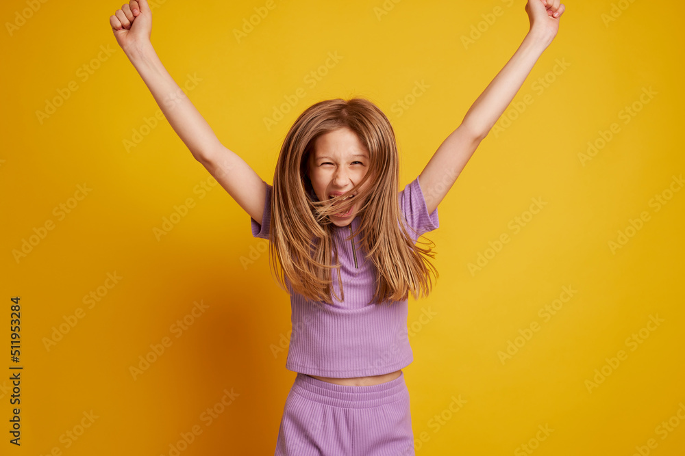 A beautiful young girl is dancing, laughing and having fun on a clean yellow background A beautiful young girl is dancing, laughing and having fun on a clean yellow background