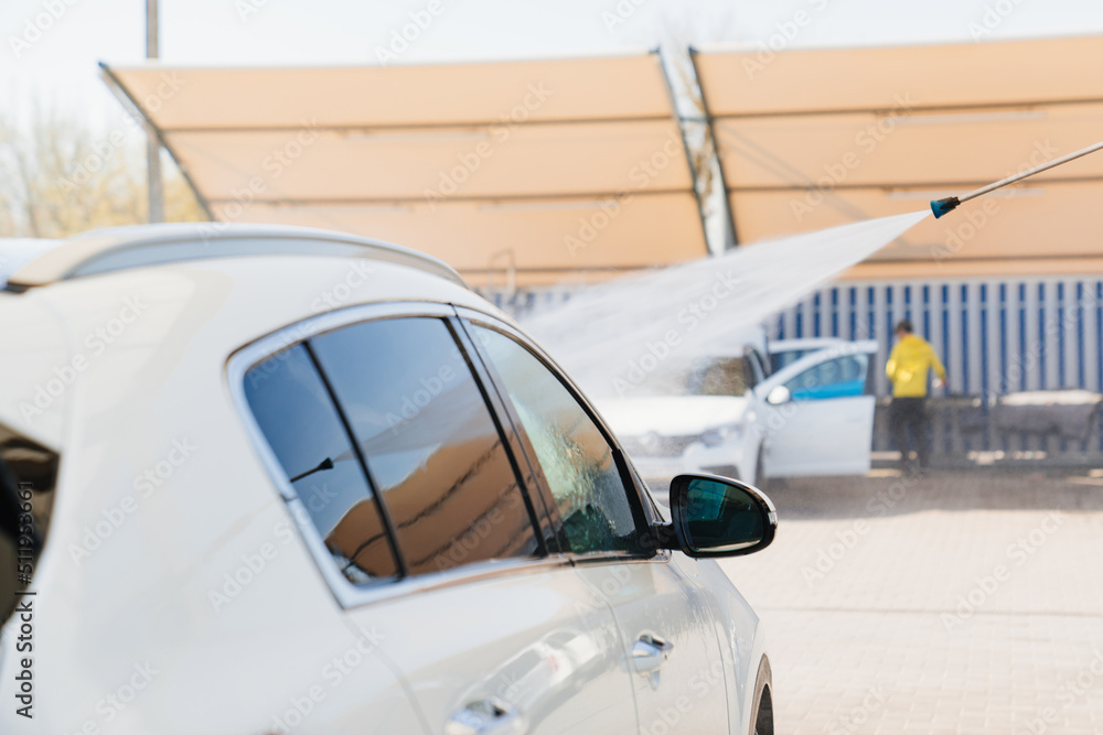 Fototapeta premium self-service car wash. a person washes the car from a hose. 