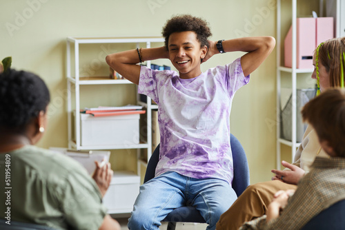 Fotografía African teenage boy sitting on chair and smiling, he behaving badly during psych