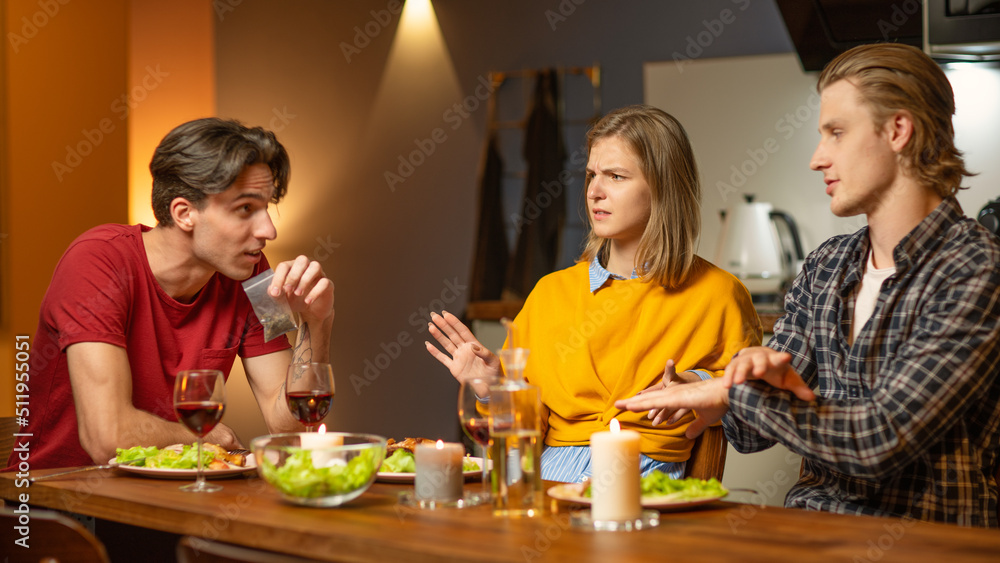 Man showing his friends a small baggie of weed during celebration dinner at home. Young people, male and female, refusing to smoke weed