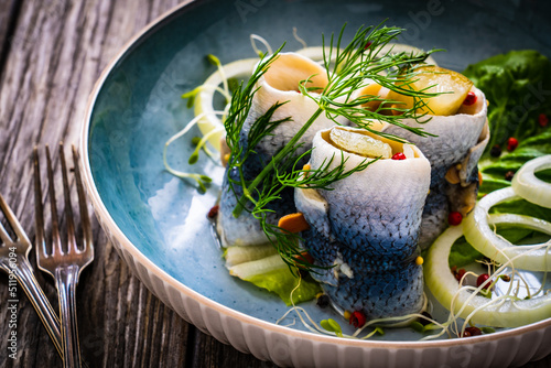Marinated herring fillets with pickled cucumber, dill and  onion on wooden table
