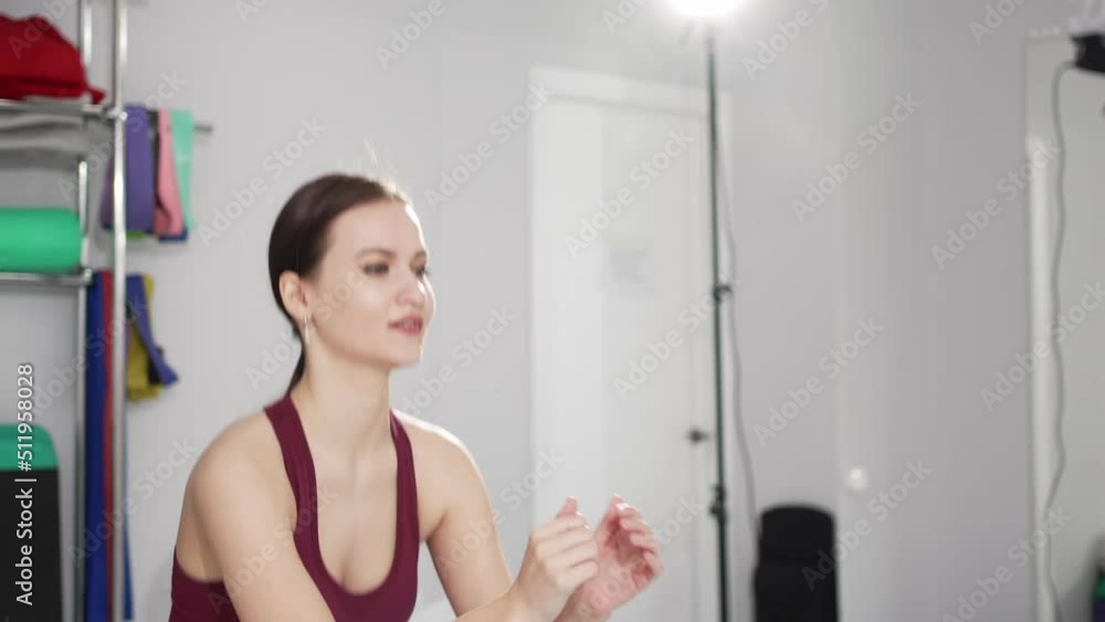 a young woman in a tracksuit does squats with gymnastic elastic bands a young woman in a tracksuit does squats with gymnastic elastic bands