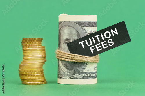 On a green surface are coins and dollars in a bundle. On the dollar sign with the inscription - Tuition Fees photo